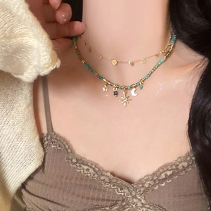 Detail of bohemian star and moon pendants on a blue beaded double-layered necklace