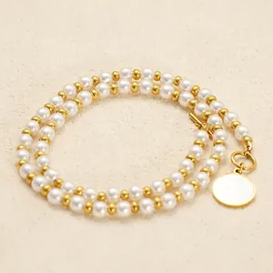 Elegant pearl necklace with golden OT buckle and round pendant on beige background