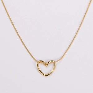 Macro shot of gold-tone hollow heart pendant on a smooth metallic snake chain