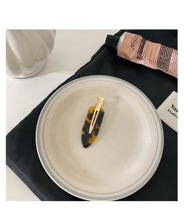 Close-up of a tortoiseshell acetate hair clip on a white ceramic tray for hair styling