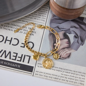 Detailed close-up of gold coin charms with heart and clover on a polished titanium steel chain