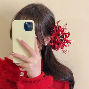 Detail view of a festive red Lycoris Radiata hair clip worn by a model in a mirror selfie