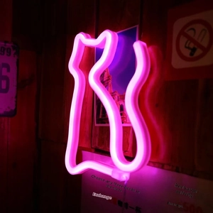 Close-up of pink LED cat-shaped neon light tube mounted on a dark wooden wall texture