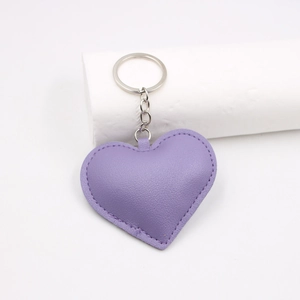 Purple heart-shaped leather keychain on white background with minimalist prop
