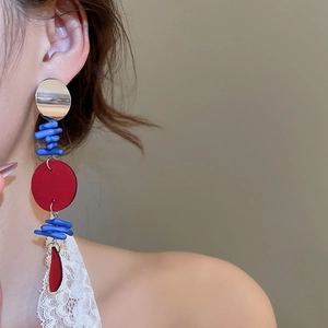 Détail de longues boucles d'oreilles avec fleurs bleues et disque rouge sur un mannequin