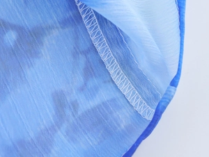Vista macro dettagliata del tessuto in chiffon con stampa blu e cuciture overlock bianche