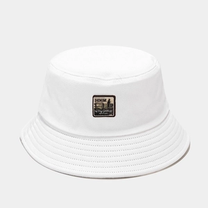 Détail du chapeau bob en toile blanche avec écusson vintage et coutures parallèles