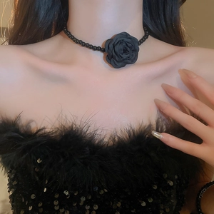 Close-up of black beaded choker with elegant fabric rose flower detail on model