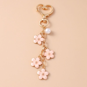 Close-up of golden heart clasp keychain with pink cherry blossoms and white pearl beads