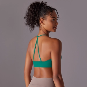 Detail view of emerald green sports bra with cross-back strap design on a female model