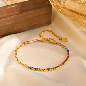 Macro shot of gold stainless steel bracelet with multicolor zircons and heart charm