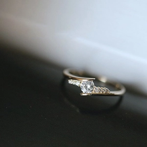 Exquisite gold twisted cross ring featuring a brilliant round center zircon and side stones