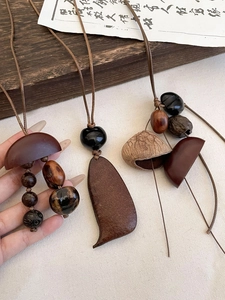 Détail de pendentifs vintage en bois avec graines naturelles et cordon tissé main