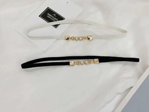 Close-up of black and white elastic belts with gold buckles and pearl accents