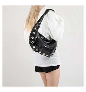 Detail of black glossy crescent shoulder bag with metallic stud embellishments and silver rivets