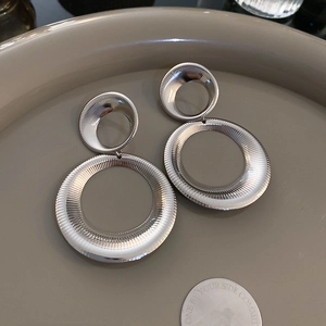 Macro detail of silver geometric double hoop earrings with radiant textured metallic finish