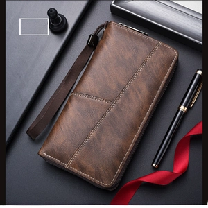 Detail of deep brown leather wallet with stitching and wrist strap on dark background
