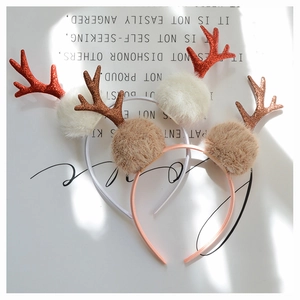 Detail of Christmas reindeer antlers headband with glitter finish and soft pom poms