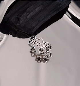 Macro shot of silver punk heart rings on reflective metal tray with artistic wood props