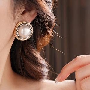 Gros plan de boucles d'oreilles vintage en perles avec texture dorée sur le mannequin