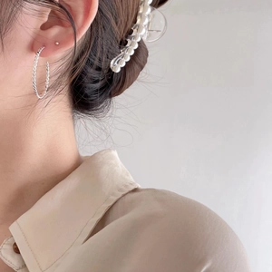 Close-up of twisted silver hoop earrings and white pearl hair clip on model