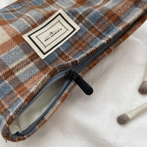 Detail of plaid tweed makeup bag with PLEASANT TIME label and secure black zipper