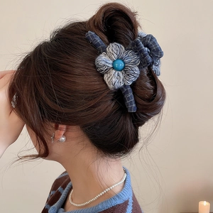 Detail of a blue knitted flower hair claw clip worn by a model for elegant hairstyle styling