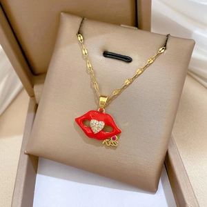 Macro shot of gold necklace with red lips pendant and heart-shaped zircon in display box