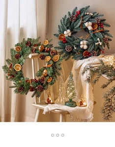 Detail of Christmas wreath with pine cones, dried orange slices and berries on a white chair