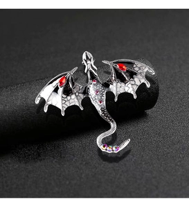 Detailed close-up of a silver dragon brooch featuring red gems and colorful rhinestones