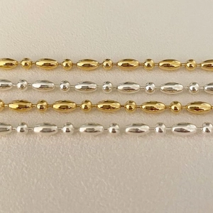 Close-up of gold and silver beaded 925 sterling silver chain with polished metal beads