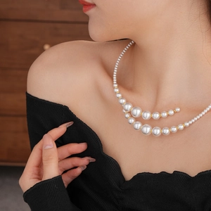 Elegant multi-size pearl choker with golden metal accents worn on a female model