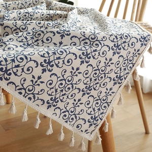 Blue damask pattern linen table runner with tassels draped over a wooden chair