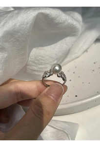 Detailed close-up of a silver lace ring featuring a large grey pearl and sparkling zircon accents