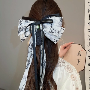Detail of satin bow hair claw with bamboo print, black tassels, and pearl beads charms