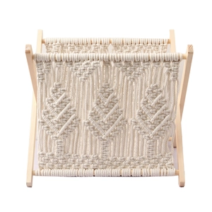 Detail of Nordic macrame cotton rope magazine rack with bohemian woven pattern on wood frame