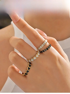 Macro shot of gold heart rings with black and white enamel details on female hand