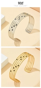 Détail de bracelets joncs superposés en or et argent avec accents en émail noir