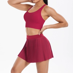 Detail of dark red high-waisted pleated athletic skirt and matching sports crop top