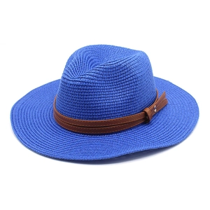 Gros plan du chapeau de paille bleu avec bande en cuir marron et détails cousus