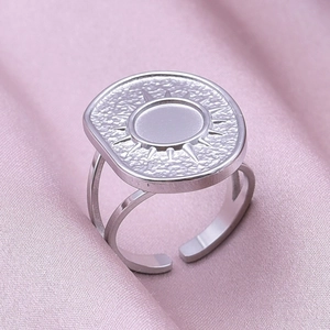 Macro detail of silver geometric sunburst ring on elegant soft pink silk fabric background