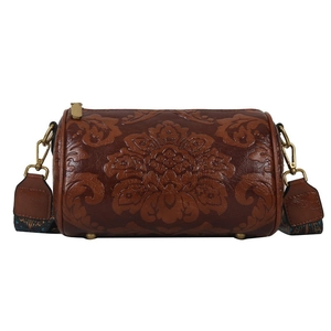 Detail of embossed floral pattern on retro brown cylinder bag with gold hardware