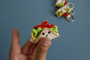 Close-up of a handmade crochet taco keychain held in hand to show its mini size