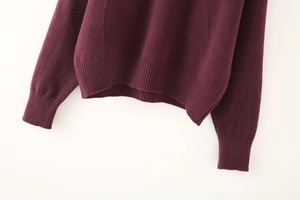 Detailed view of the ribbed hem and cuffs on a soft dark purple knit sweater