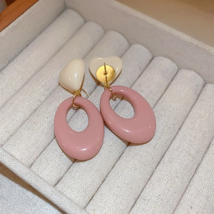 Detail of sweet heart-shaped resin earrings with oval hoops in cream and dusty pink tones