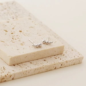 Close-up of minimalist S925 sterling silver ball stud earrings on stone display