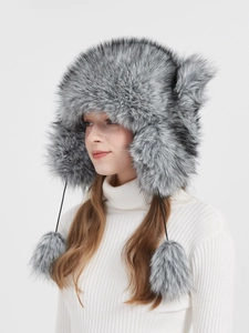 Detailed side view of grey faux fox fur winter trapper hat with pom-pom drawstrings