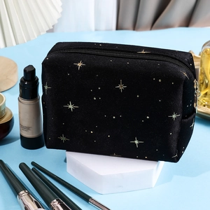 Detail of black velvet cosmetic bag featuring gold foil stars and secure zipper closure