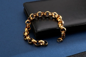 Macro view of golden stainless steel link bracelet with clasp on black leather