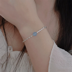 Close-up of bamboo-shaped silver metal tube bracelet with a blue gemstone bead